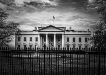 Black and white image of the United States presidential residence with flag on roof in the nations capital